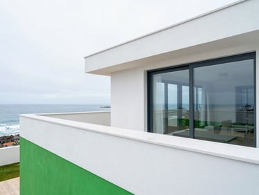 Architectural shot of a modern coastal villa terrace in Foz do Douro, clean lines, repelled water droplets visible on the surface, bright daylight.