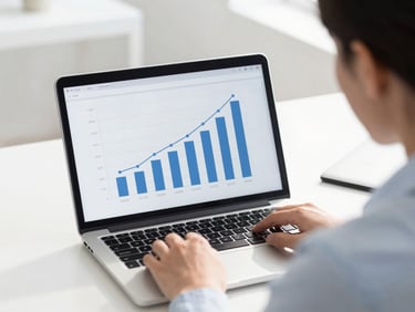 Over the shoulder view of a business owner reviewing a simple, clear traffic growth chart on a laptop screen, bright natural daylight, clean modern desk workspace