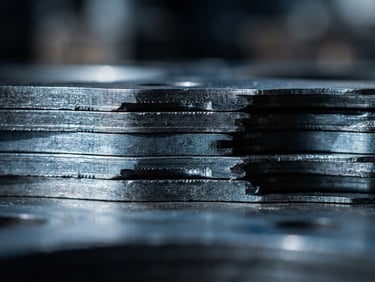 Industrial macro photography of multi-layer steel gasket edges stacked, high-contrast dramatic side-lighting, cool metallic steel tones, sharp focus on material texture, 50mm