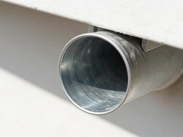 Close-up macro shot of the same gutter completely cleared, clean metallic interior, pristine downspout opening, bright midday sun