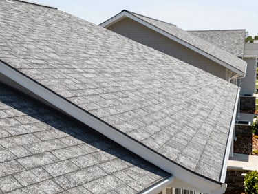 Wide-angle shot of the same residential roofline, gutters perfectly clean and aligned, pristine shingles, bright daylight