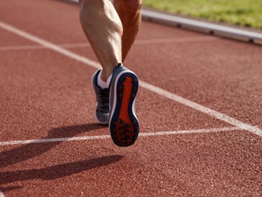 Low angle view of an athlete's foot plant during a sprint on an outdoor track, natural afternoon light raking across the lane markings, sharp focus on the shoe grip and ankle drive