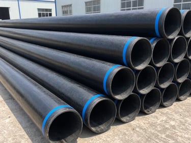Industrial warehouse setting showing neatly stacked large-diameter black HDPE pipes with blue stripes, clean industrial composition, bright natural light.