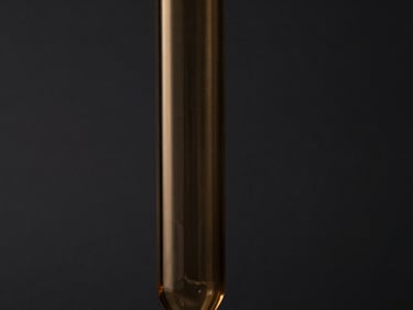 Moody close-up of a geometric glass pipe silhouette against a dark charcoal background, warm amber accent lighting, sharp focus, high-contrast, 50mm lens