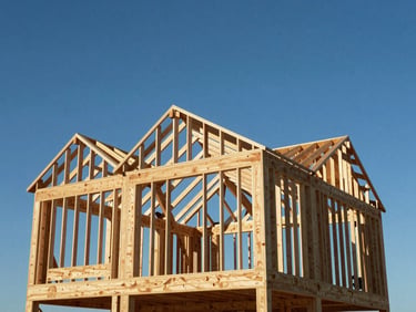 Wide heroic shot of a custom home framing structure under a clear blue sky, perfectly plumb rafters and joists