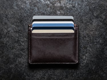 Overhead macro flat-lay of a minimalist wallet stuffed with ten cards, showing its incredibly slim profile against a dark textured steel background.