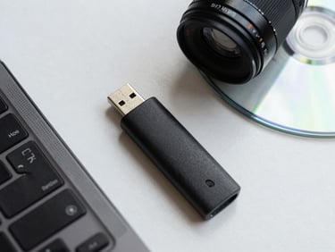 Close-up of USB drive and driver pack CD on a white desk surface, overhead catalog angle, even bright lighting