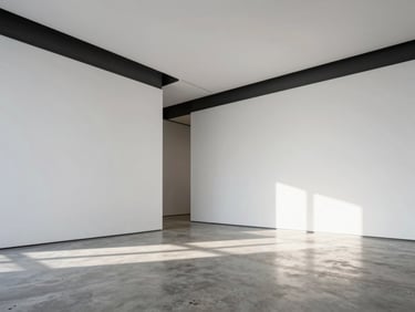 Wide-angle architectural shot of a modern gallery space with pristine white walls, sharp charcoal trim, and natural light streaming onto a polished concrete floor.