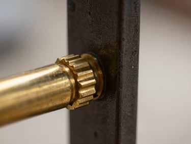 Extreme close-up of a hand-patinated brass joint meeting dark architectural steel, flawless alignment, dramatic side-lighting, editorial luxury.