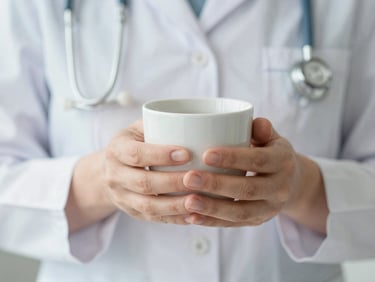 Soft focus close-up of hands gently holding a warm cup, diffused natural light, calming tones, no faces