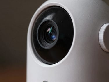 Close-up of an app-free baby monitor camera lens, textured white casing, physical dial controls, moody high-contrast lighting