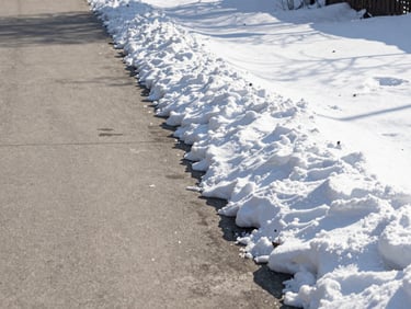 A clean, perfectly cleared concrete walkway in winter, crisp snow stacked neatly to the side, bright morning sun, no ice