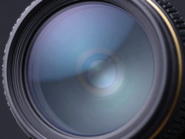 Macro shot of a clear optical lens reflecting subtle blue light, with a faint gold accent on the frame edge, sharp studio lighting, high-contrast, deep navy and gold accents, crisp detail