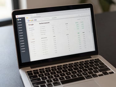 Close-up overhead view of a laptop screen displaying a Google Ads performance dashboard with clear CTR and conversion metrics, on a clean dark desk, sharp daylight from the left, data legible and crisp
