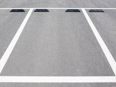 Straight-on shot of modern parking tiles, textured grip, industrial grey tone, bright neutral daylight, clean white and charcoal tones, sharp focus, 35mm lens