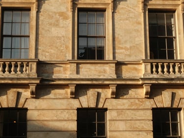Architectural detail of a premium historic estate facade, warm limestone, low-angle golden hour natural sunlight, soft shadows.