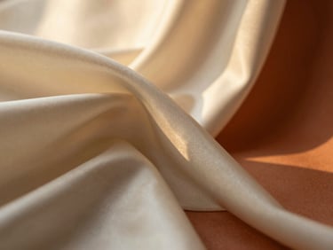 Soft folds of rich ivory silk fabric catching warm golden-hour light, texture detail
