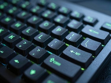 Macro close-up of a dark mechanical keyboard with glowing green LED backlight, shallow depth of field, sharp focus on the command key, cool blue and charcoal ambient tones