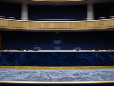 Wide environmental portrait of an empty, elegant European ministerial hall, high-contrast lighting, navy and gold accents.