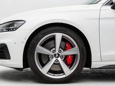 Clean white premium sedan, close-up of front wheel and brake caliper, bright daylight, professional studio lighting, 50mm