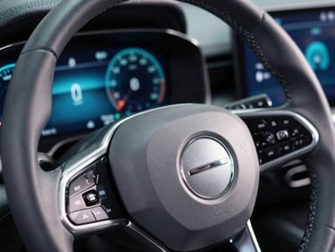 Macro close-up of a high-end vehicle steering wheel and digital dashboard showing performance telemetry, brushed silver texture