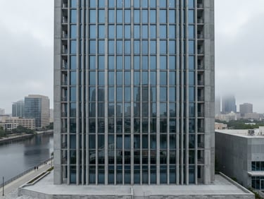 Wide-angle architectural perspective of a modern building facade with strong vertical lines, reflecting a quiet Tampa cityscape under overcast morning light. Muted desaturated blue and concrete tones, sharp focus, minimalist composition.