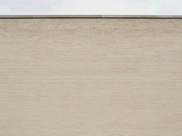 Straight-on architectural lines of a clean brick building facade, soft natural overcast daylight, muted warm neutral tones.