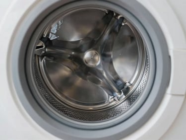 A clean, modern washing machine drum reflecting bright, sterile workshop light, representing laundry repair.