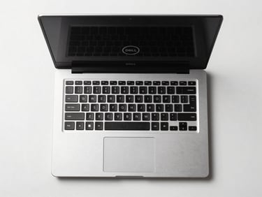 Overhead straight-down product shot of a refurbished Dell laptop open on a clean white surface, studio lighting from above, keyboard and screen visible, no hands, no props, product-hero style