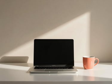 Minimalist, organized office space with a laptop, a ceramic cup, and soft morning sunlight casting gentle shadows on a sand-beige wall, 35mm
