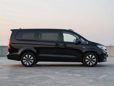Three-quarter view of a modern black multi-passenger vehicle, clean exterior, soft evening twilight, 35mm