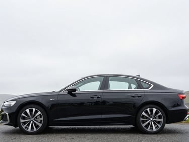 Side profile of a clean black executive saloon car, bright overcast Welsh daylight, sharp focus, cool desaturated tones
