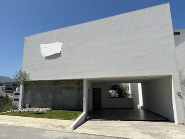 Fachada de casa blanca moderna y minimalista con techo plano y cochera cubierta bajo un cielo azul