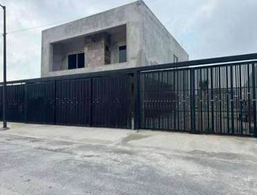 Casa moderna en obra gris con una puerta de seguridad de metal negro y entrada de auto corrediza