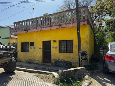 Pequeña casa amarilla de un solo piso con un balcón en la azotea y ventanas en Santiago Nuevo León