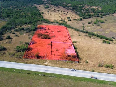 Vista aérea de una propiedad rural en venta resaltada en rojo junto a una carretera pavimentada.