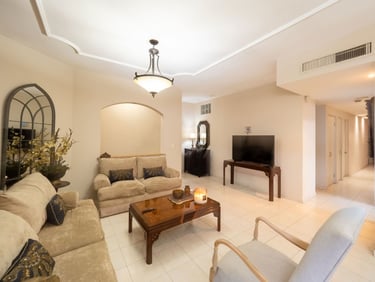 Elegante salón con sofás beige, una mesa de centro de madera y un televisor de pantalla plana