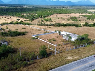 Vista aérea de un edificio abandonado y terreno rural cerca de una carretera, con un camión