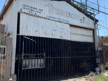 Edificio de almacén industrial en Monterrey con portones de metal y líneas eléctricas aéreas.