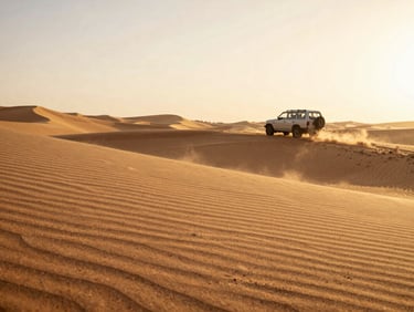 Warm golden hour light hitting sand dunes, a luxury vehicle parked off-road in the distance