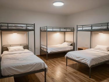 A spacious triple sharing room for students with three neatly made beds, individual study lamps, and clean wooden flooring.