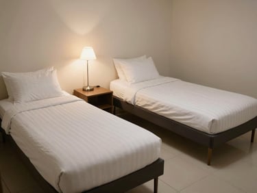 A tidy double sharing room with two single beds, individual study lamps, and clean tiled flooring under soft ambient light.