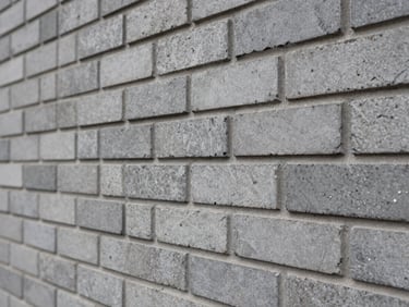 Close-up architectural detail of premium hand-cut grey brickwork, precise mortar lines, soft overcast daylight highlighting the rough texture.