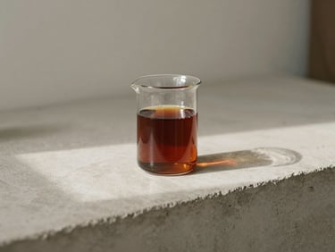A glass beaker filled with rich walnut dye sitting on a concrete studio counter, soft directional shadow, minimalist aesthetic.
