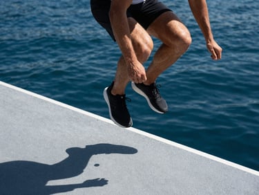 Close-up of an athlete performing explosive lateral jumps on a platform, sharp midday shadows, focused physical tension, high-contrast sports photography