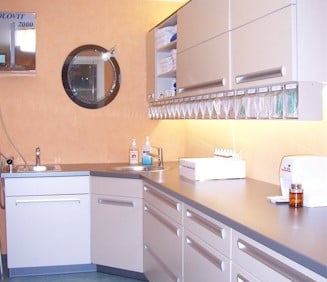Modern medical clinic storage cabinets and integrated sink area with clinical supplies for a doctor office.