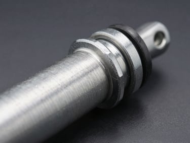 Macro close-up of a sturdy steel shock absorber cylinder, focus on the clean metallic threads and black rubber seal, bright workshop lighting