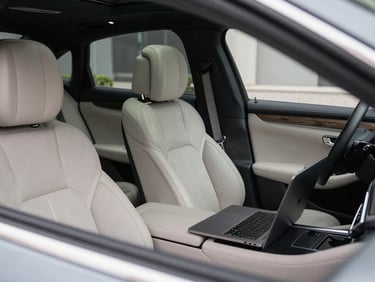 Pristine interior of a luxury sedan highlighting leather stitching, executive amenities, and a laptop open on the rear seat, clean low-key lighting.