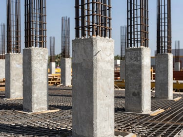 Close-up of reinforced concrete columns and rebar grid on a large commercial building site, north-facing daylight, sharp structural texture, organized steel ties visible