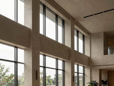 Interior shot of a modern, high-ceilinged lobby in a commercial building, minimalist design, soft natural light through large windows, muted earth tones, medium format, bleeding to the right edge.